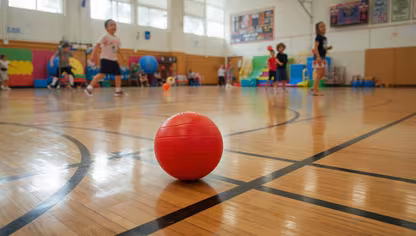 PE Dodgeball on a gym floor with kids in gym class running around it